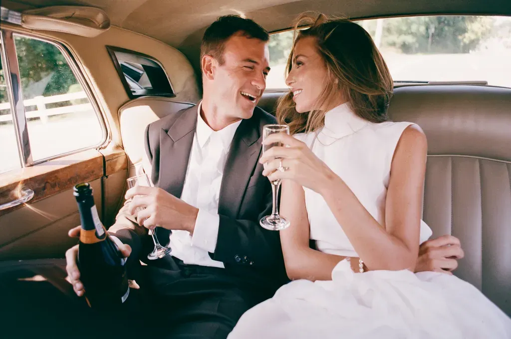 Paige Lorenze Tommy Paul Champagne Vintage Rolls Royce Paige Lorenze and Tommy Paul laughing with champagne in the back seat of a vintage classic Rolls Royce