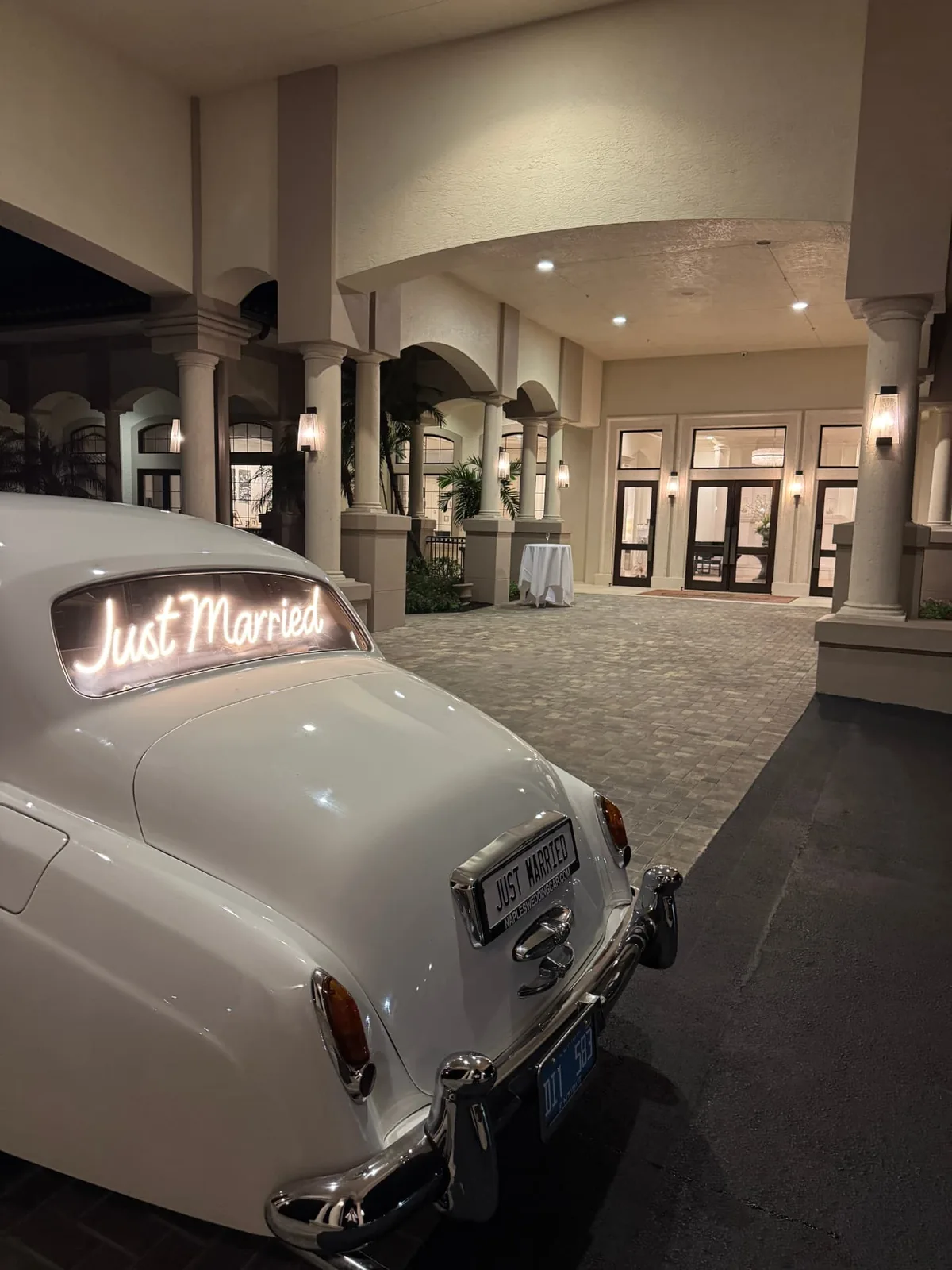 Rear view of a cream white vintage Rolls-Royce Silver Cloud II with a glowing Just Married script and plate at the Hyatt Regency Coconut Point Resort and Spa in Bonita Springs Florida