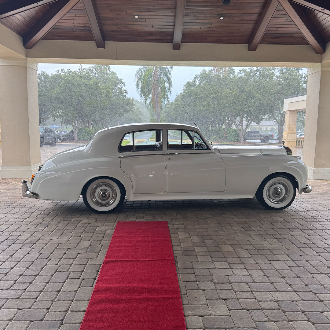 Vintage white Rolls Royce Silver Cloud II on a red carpet beneath the porte-cochere at Vineyards Country Club in Naples, Florida