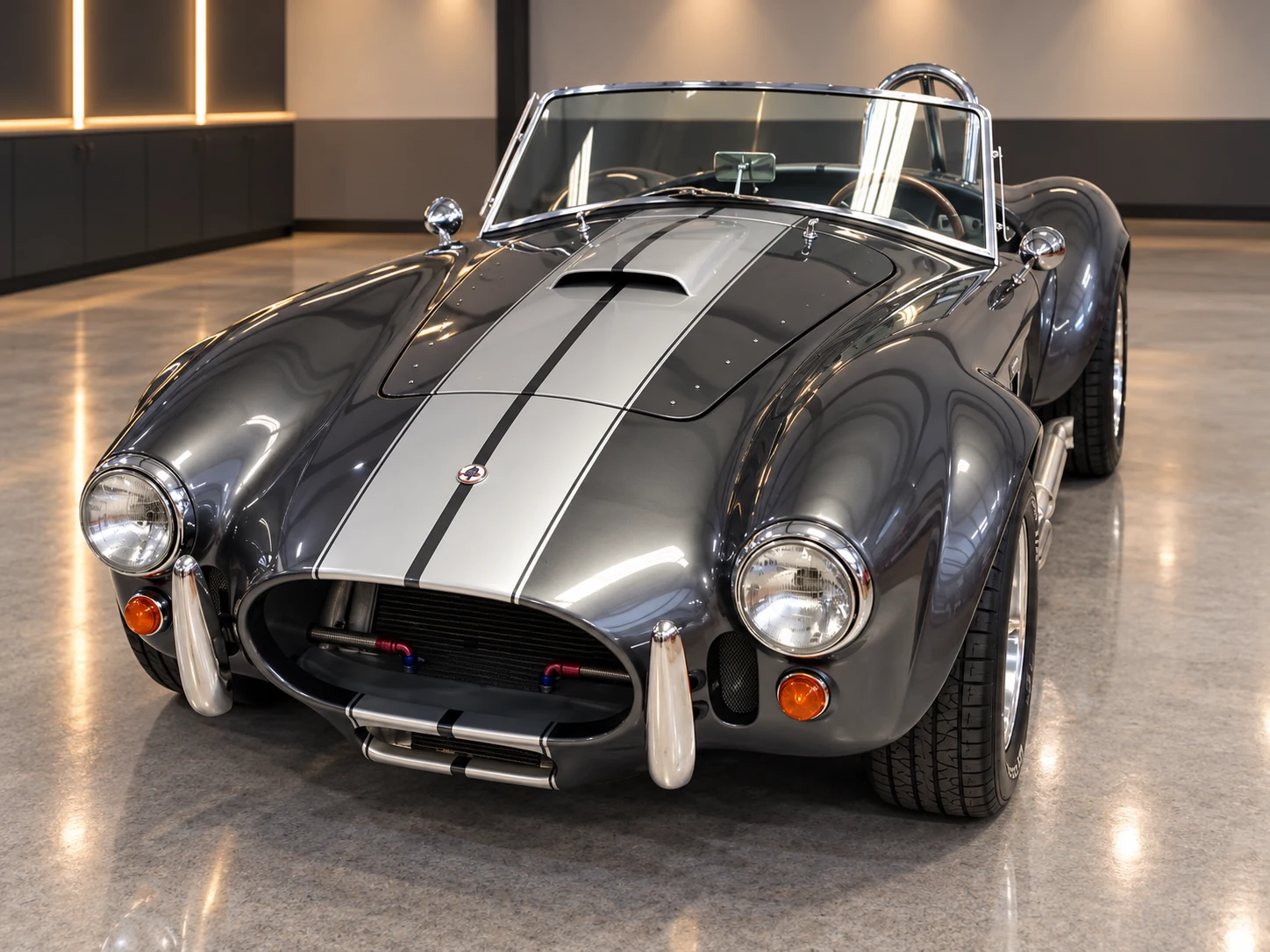 Dark grey metallic 1965 Shelby Cobra replica with a silver racing stripe, chrome bumpers and roll bar, photo session car in Naples Florida