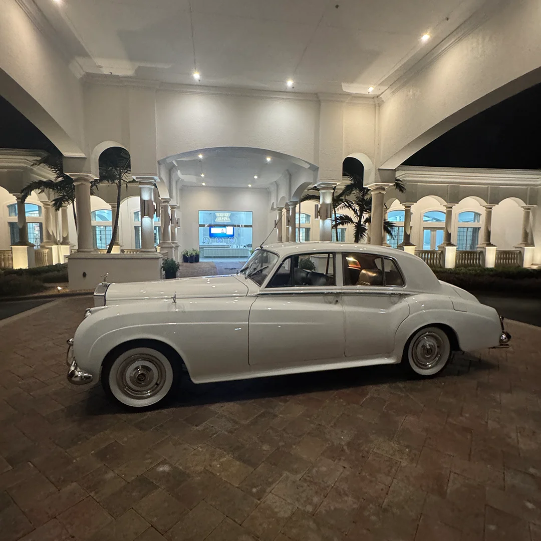 Rolls-Royce Silver Cloud II Side Profile The Strand Naples FL Side profile of vintage white 1960 Rolls-Royce Silver Cloud II wedding getaway car parked beneath the illuminated arched portico at The Strand in Naples Florida