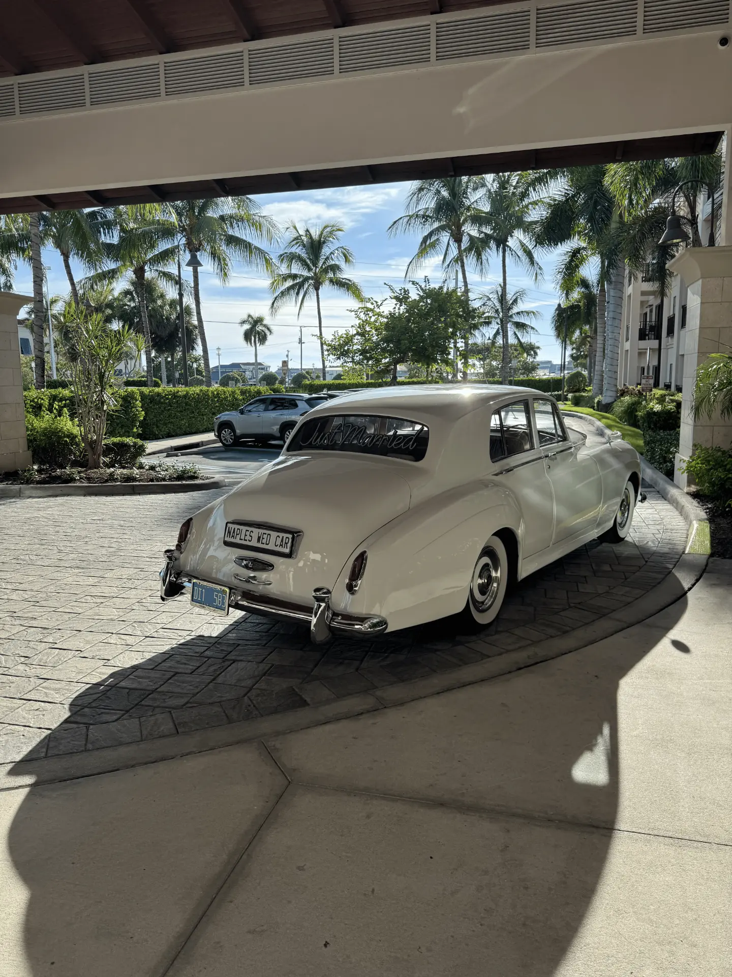 Just Married Rolls-Royce Naples Wed Car Plate Naples Florida Wedding Rear view of a cream white vintage Rolls-Royce Silver Cloud II with a Just Married rear window script and Naples Wed Car plate in Naples Florida