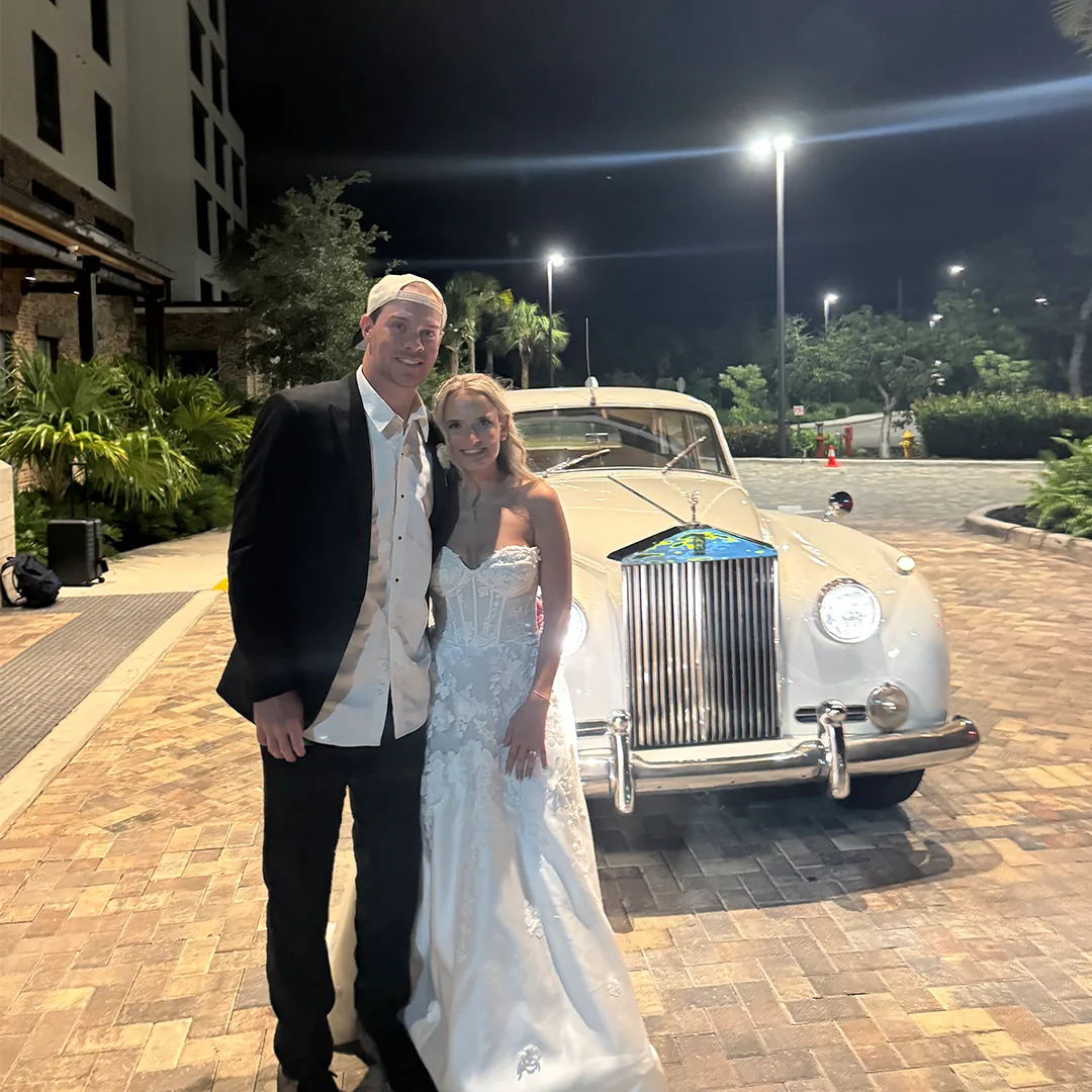 Rieth Wedding Couple Rolls-Royce Getaway The Strand Naples FL Bride and groom smiling in front of a vintage cream white 1960 Rolls-Royce Silver Cloud II wedding getaway car at The Strand in Naples Florida