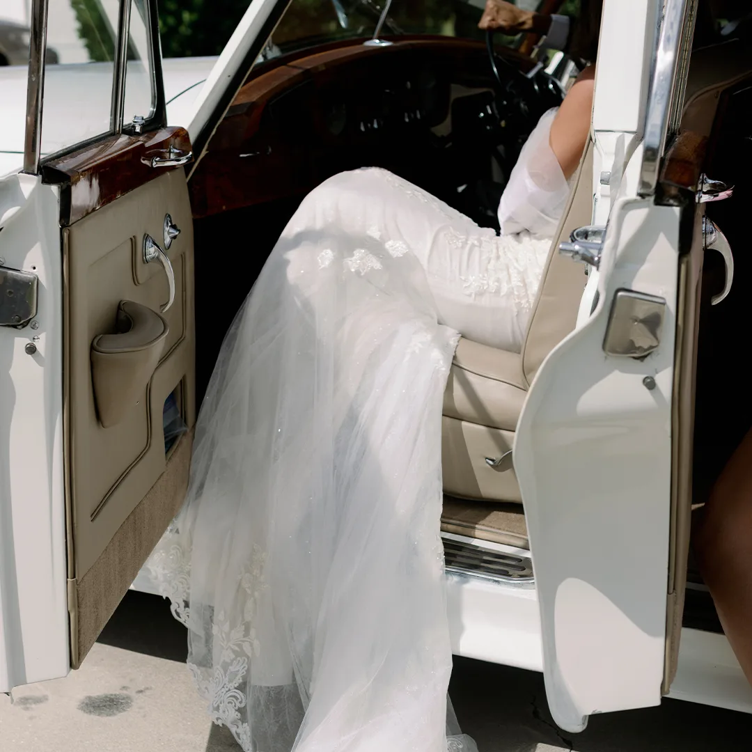Bride Wedding Gown Rolls Royce Silver Cloud II Open Door Rock Manor Fort Myers Florida Wedding Car Bride in her wedding gown beside the open door of a vintage cream white Rolls Royce Silver Cloud II at Rock Manor in Fort Myers, Florida