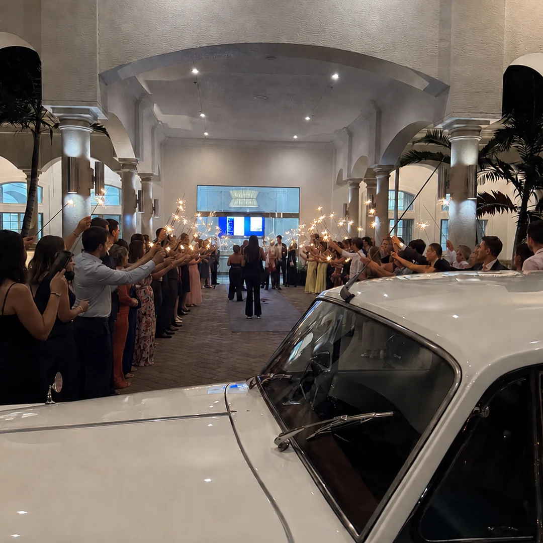 Sparkler Send Off Rolls-Royce Wedding Getaway The Strand Naples FL Wedding guests forming a sparkler tunnel send off next to a vintage white 1960 Rolls-Royce Silver Cloud II at The Strand in Naples Florida