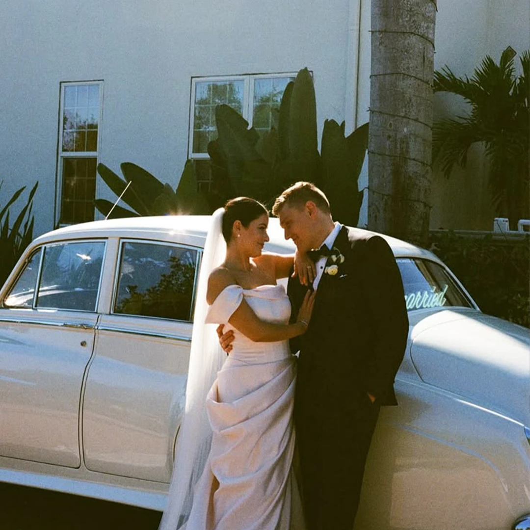 Bride and groom embracing beside a vintage white Rolls Royce Silver Cloud II at Shangri-La Springs in Bonita Springs, Florida