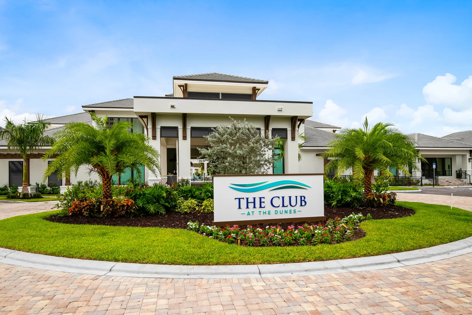 The Club at the Dunes wedding venue — elegant modern clubhouse entrance with branded sign and tropical landscaping in Naples, Florida