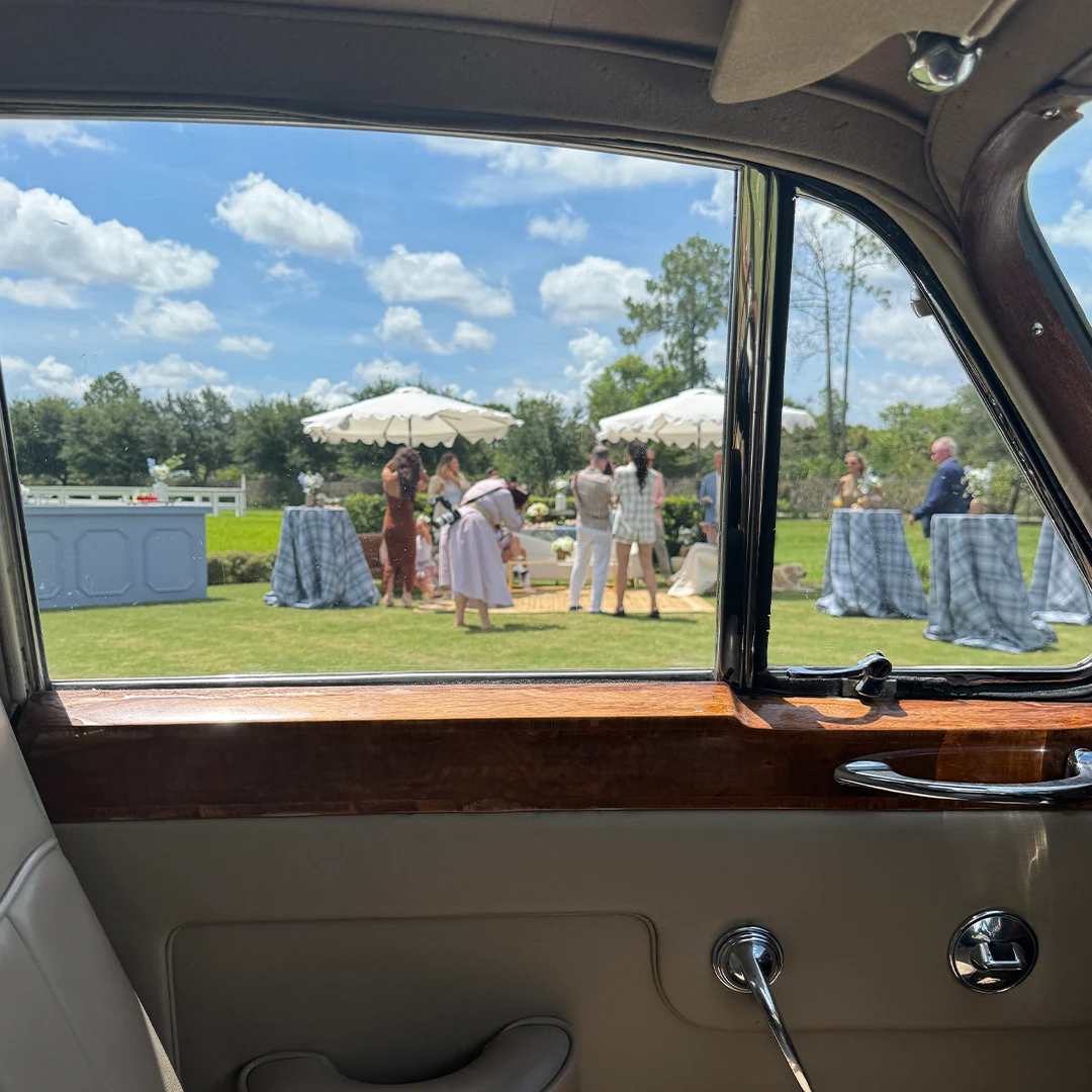 View of a Shore Acres Farm wedding reception through the window of a vintage Rolls Royce Silver Cloud II