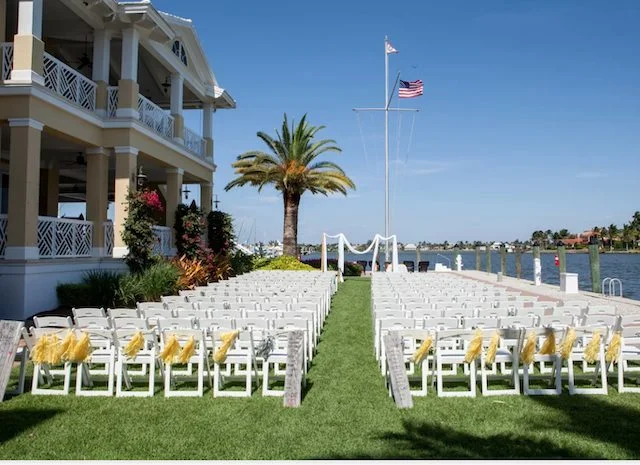 Naples Yacht Club wedding venue — waterfront ceremony lawn overlooking Naples Bay with palm trees and the historic clubhouse in Naples, Florida