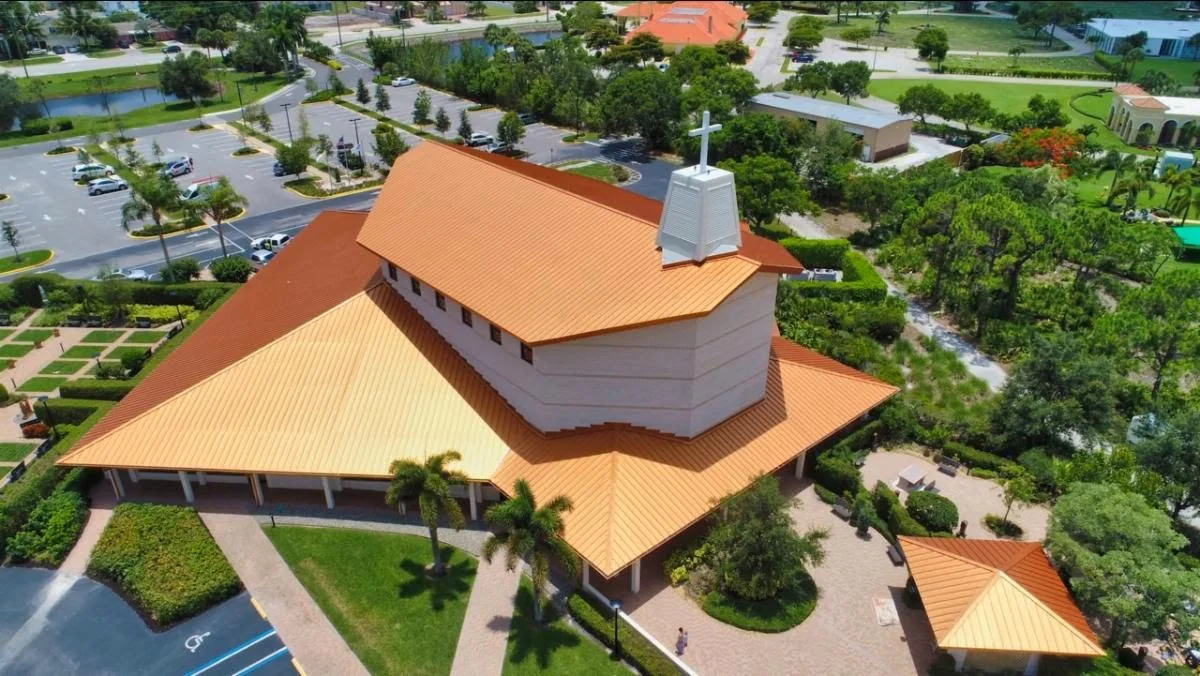 Saint John the Evangelist Catholic Church wedding venue — aerial view of the copper-toned roof, white steeple, and manicured grounds in Naples, Florida