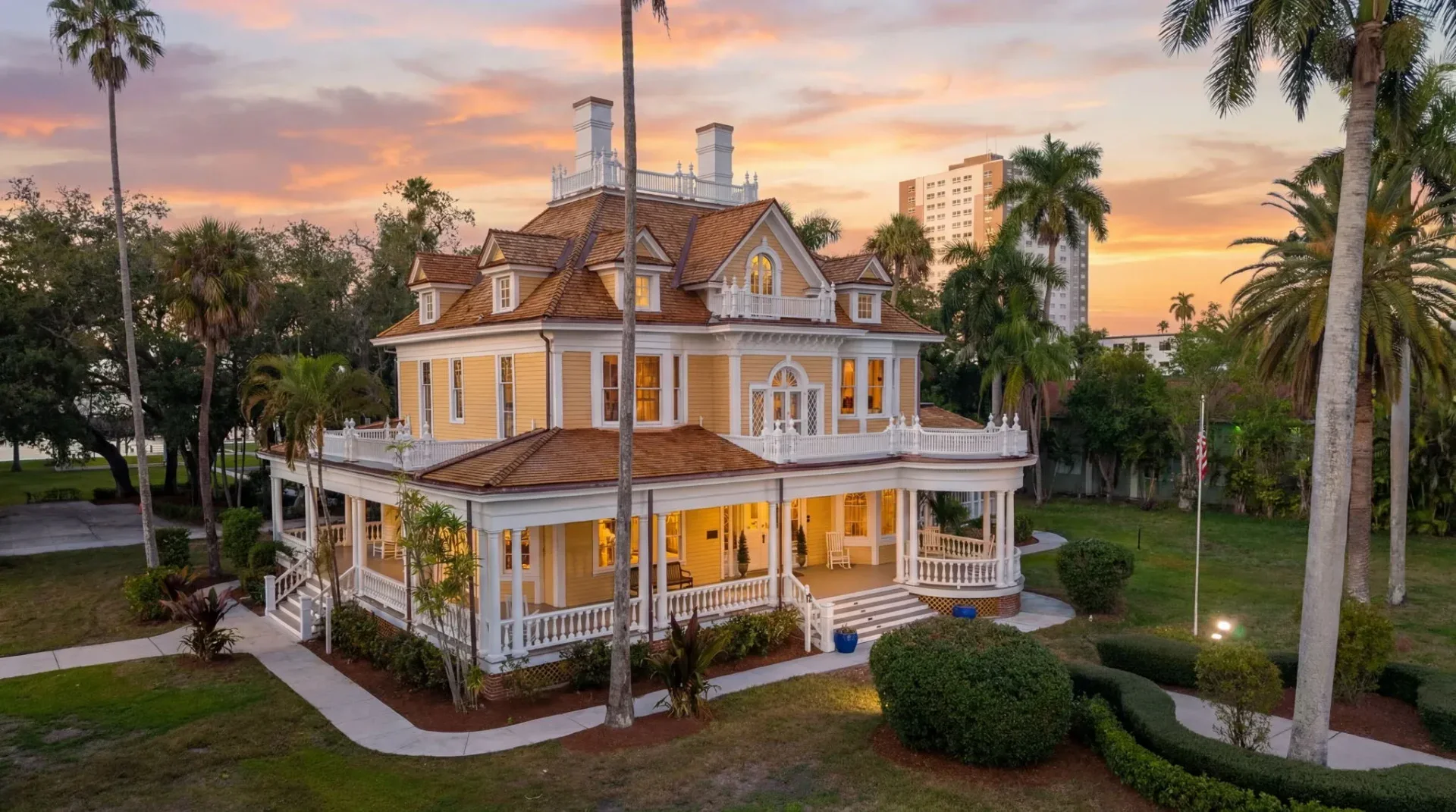 Burroughs Home and Gardens wedding venue — historic yellow Victorian estate with wraparound veranda, white trim, terracotta roof, and palm trees at golden hour in Fort Myers, Florida