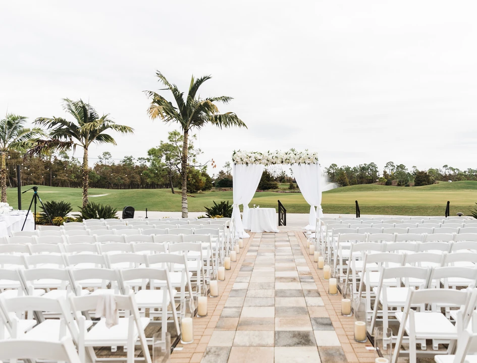 The Club at Olde Cypress wedding venue — open-air ceremony aisle lined with white chairs leading to a floral draped arch overlooking the golf course in Naples, Florida