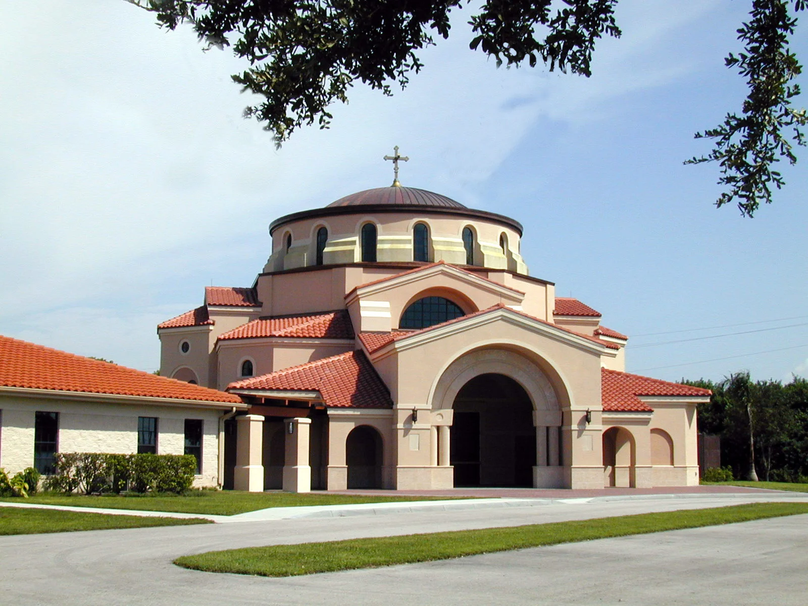 St. Katherine Greek Orthodox Church wedding venue — Byzantine-style dome and terracotta tile roof framed by oak branches in Naples, Florida