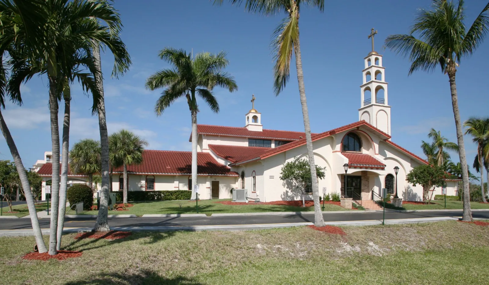 San Marco Catholic Church wedding transportation on Marco Island, Florida — white Spanish mission church with red tile roof and bell tower framed by royal palms