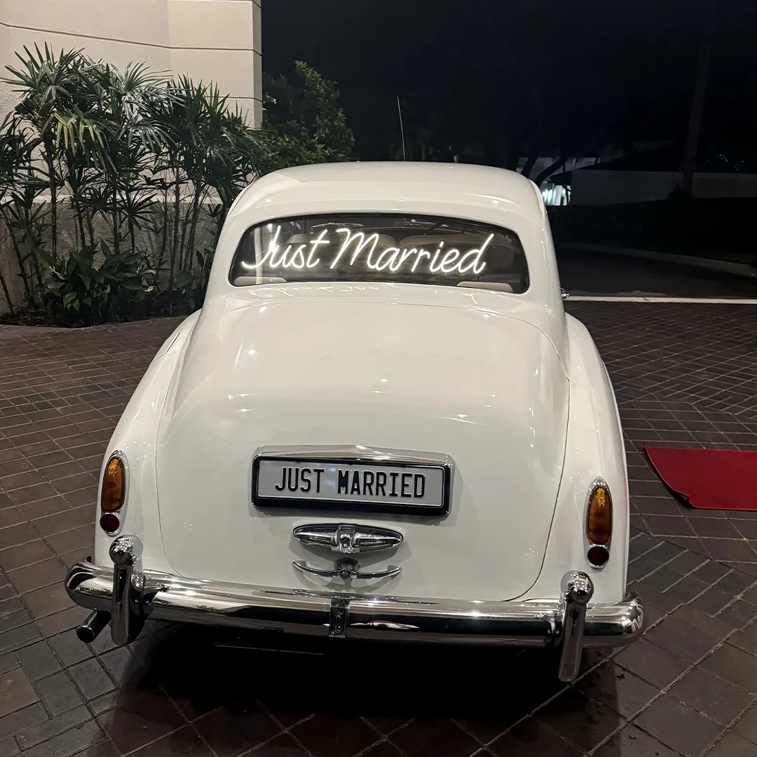 Just Married Rolls Royce Silver Cloud II Night Getaway Palmira Golf Club Bonita Springs Florida Newlyweds beside a vintage cream white Rolls Royce Silver Cloud II with a glowing Just Married sign on their wedding night at Palmira Golf Club in Bonita Springs, Florida