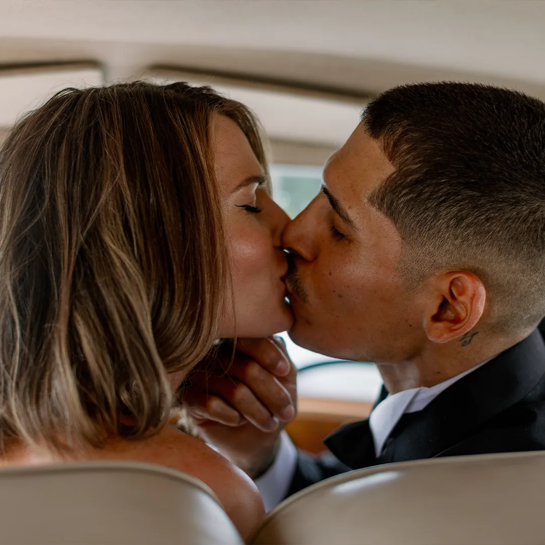 Bride and Groom Kiss Inside Rolls Royce Silver Cloud II First Ride Wedding Southwest Florida Bride and groom sharing a kiss inside the back seat of a vintage cream white Rolls Royce Silver Cloud II after their wedding ceremony in Southwest Florida