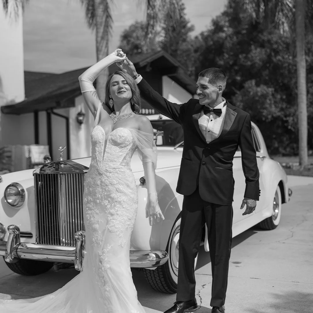 Black and white photo of a bride and groom dancing in front of the vintage Rolls Royce Silver Cloud II at a 1920s era styled shoot at Rock Manor