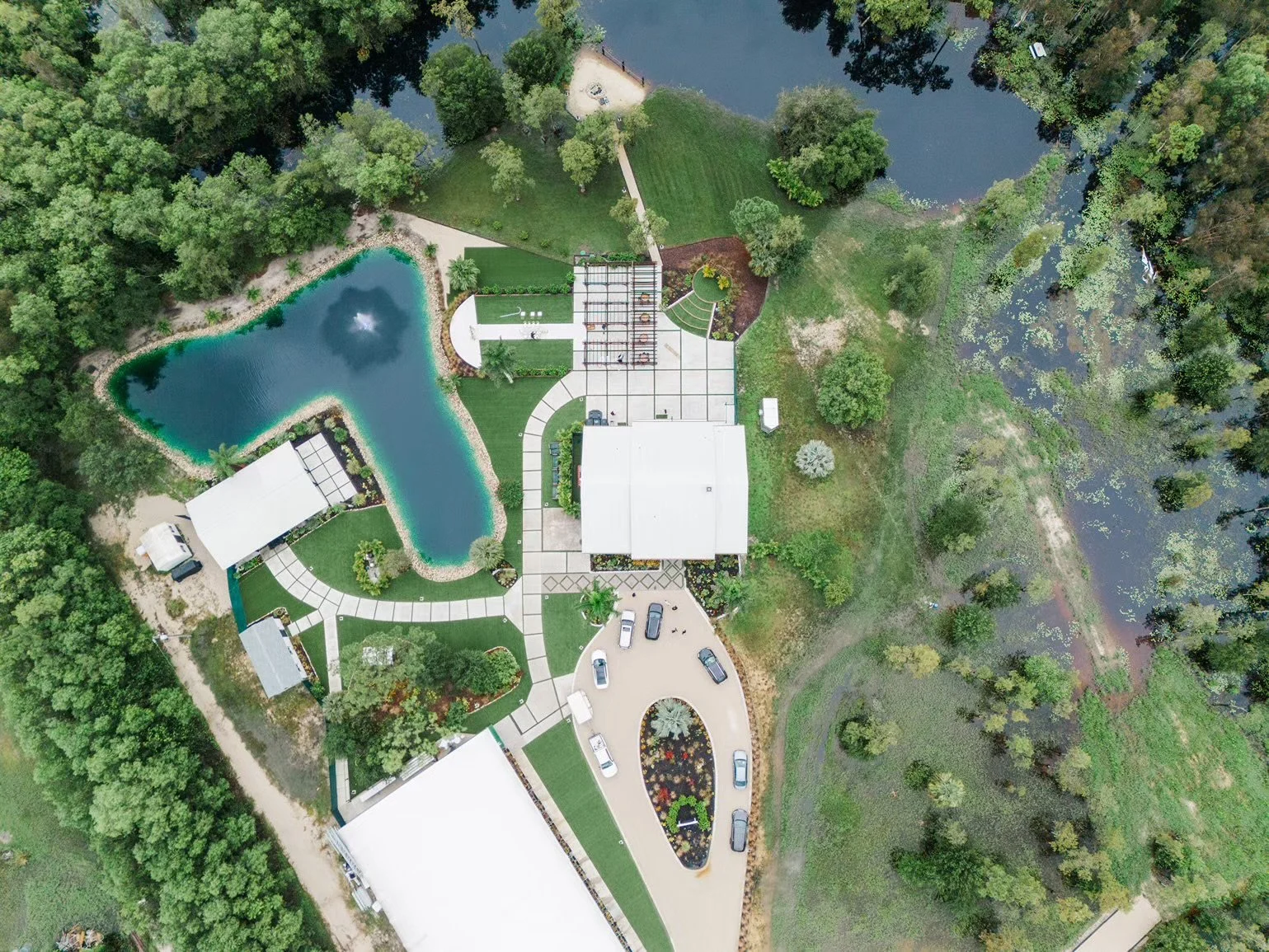 Corkscrew Weddings & Winery Wedding Venue — Estero, FL Corkscrew Weddings & Winery wedding venue — aerial view of the white estate, turquoise pond with fountain, manicured lawns, and surrounding tropical greenery in Estero, Florida