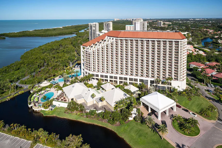 Naples Grande Beach Resort Wedding Venue — Naples, FL Naples Grande Beach Resort wedding venue — aerial view of the soaring white tower with terracotta roof, tropical pools, mangrove estuaries, and Gulf of Mexico shoreline in Naples, Florida