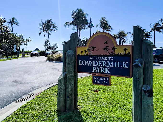 Lowdermilk Park wedding venue — wooden welcome sign with palm trees and the entrance to the Naples beach park