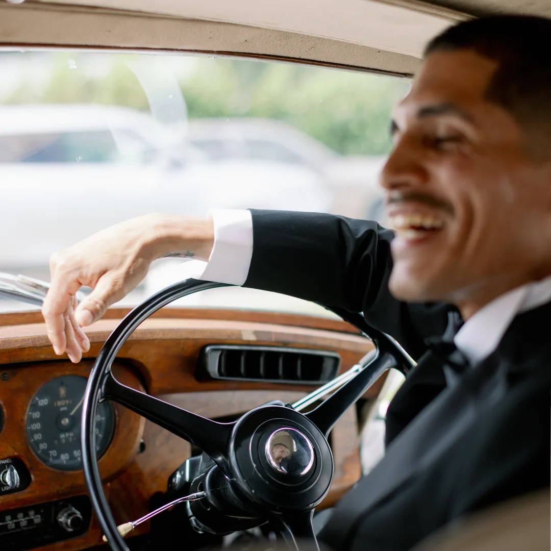 1960 Rolls Royce Silver Cloud II Chauffeur Steering Wheel Wood Dashboard Naples Florida Chauffeur in a suit and tie smiling beside the wood dashboard and steering wheel of the vintage 1960 Rolls Royce Silver Cloud II in Naples, Florida