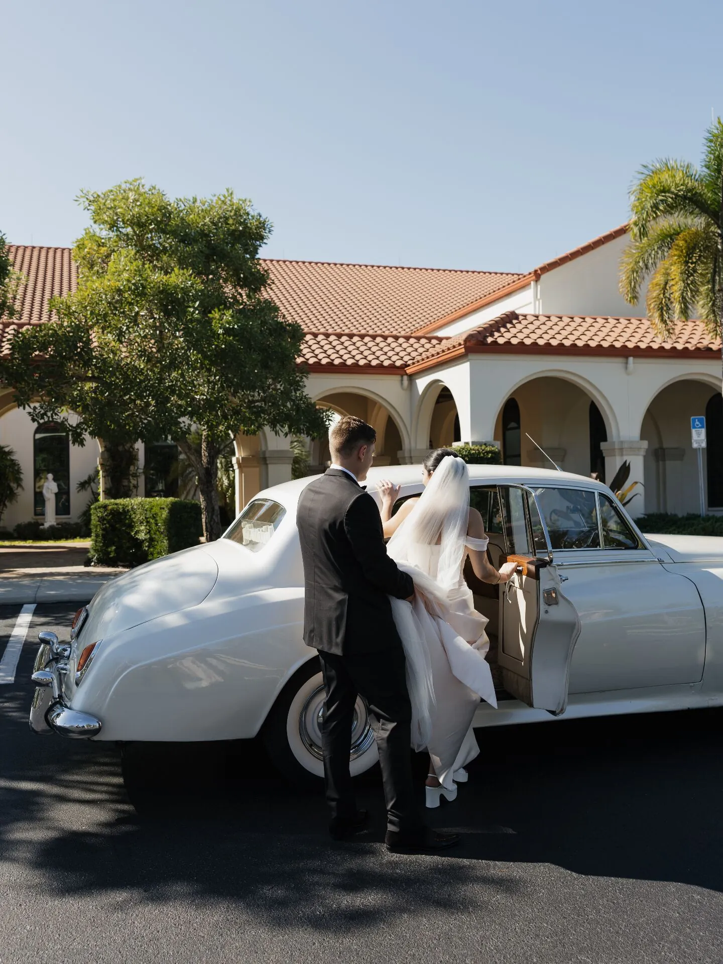 Couple entering vintage Rolls-Royce getaway car at Marco Island wedding ceremony