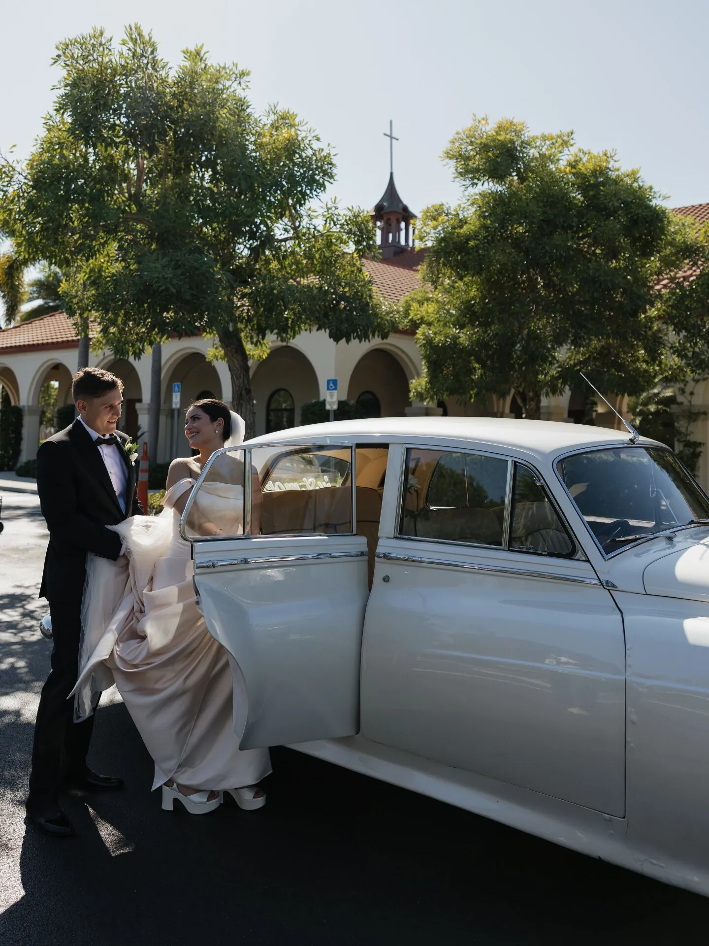 Groom helping bride into Rolls-Royce wedding car outside Southwest Florida church venue